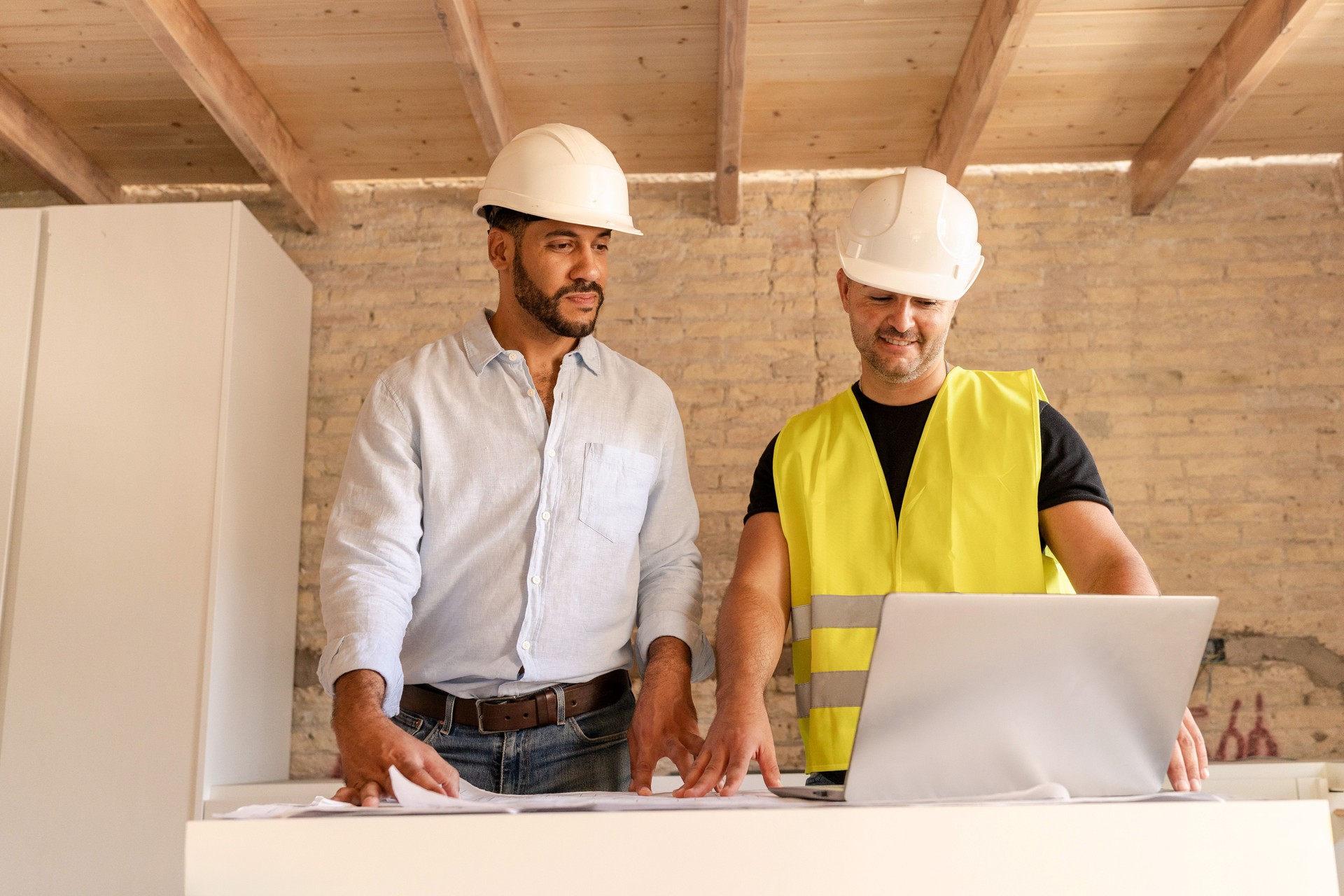 Construction workers discussing renovation house with customer using laptop at building site